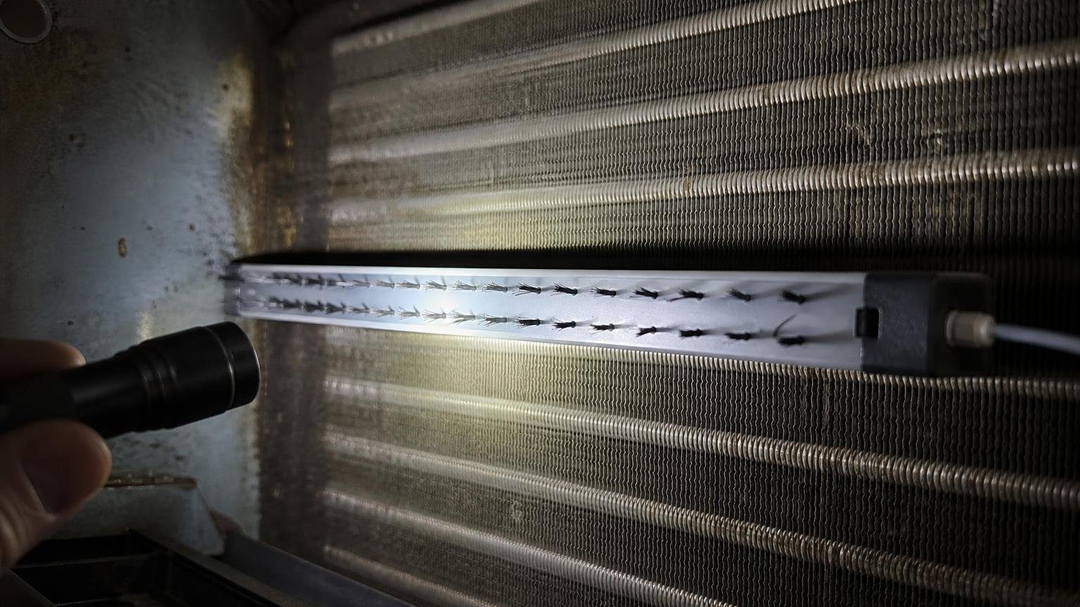 Technician inspecting an air handler where a bipolar ionization unit would be installed