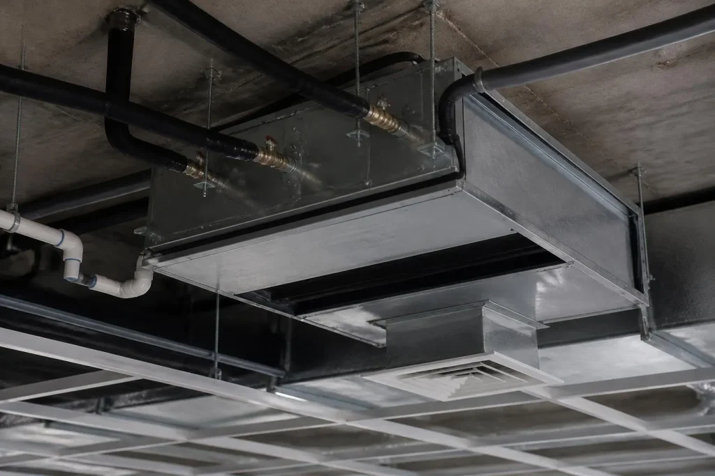 A horizontal fan coil above the ceiling: water pipes in, conditioned air out to the diffuser.