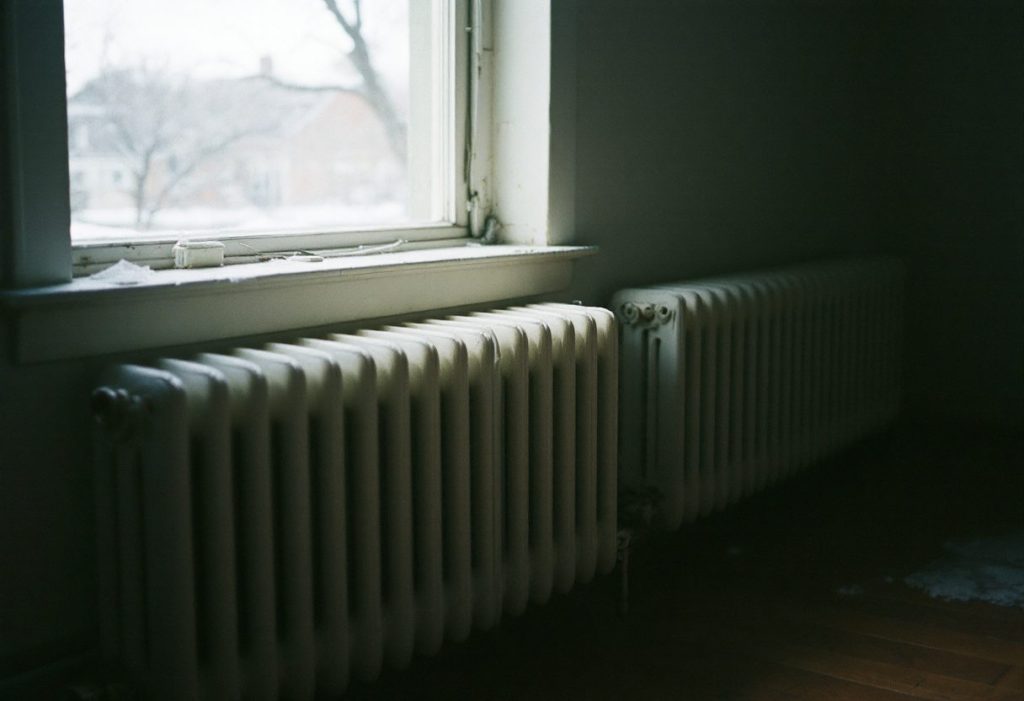 Cast iron radiators under a window in an older home, fed by a boiler.